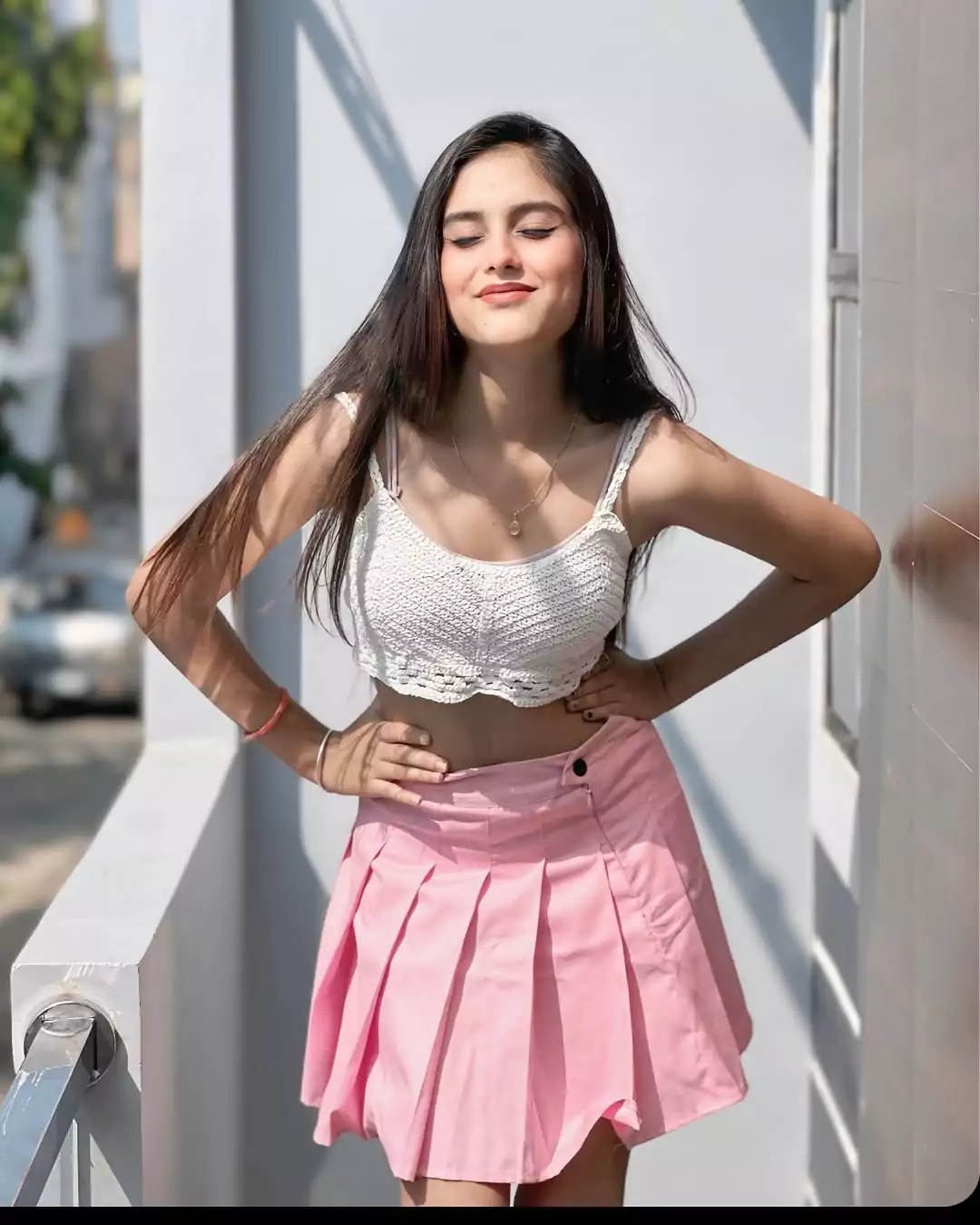 A young woman in a pink skirt poses for the camera and style in her fashionable outfit.