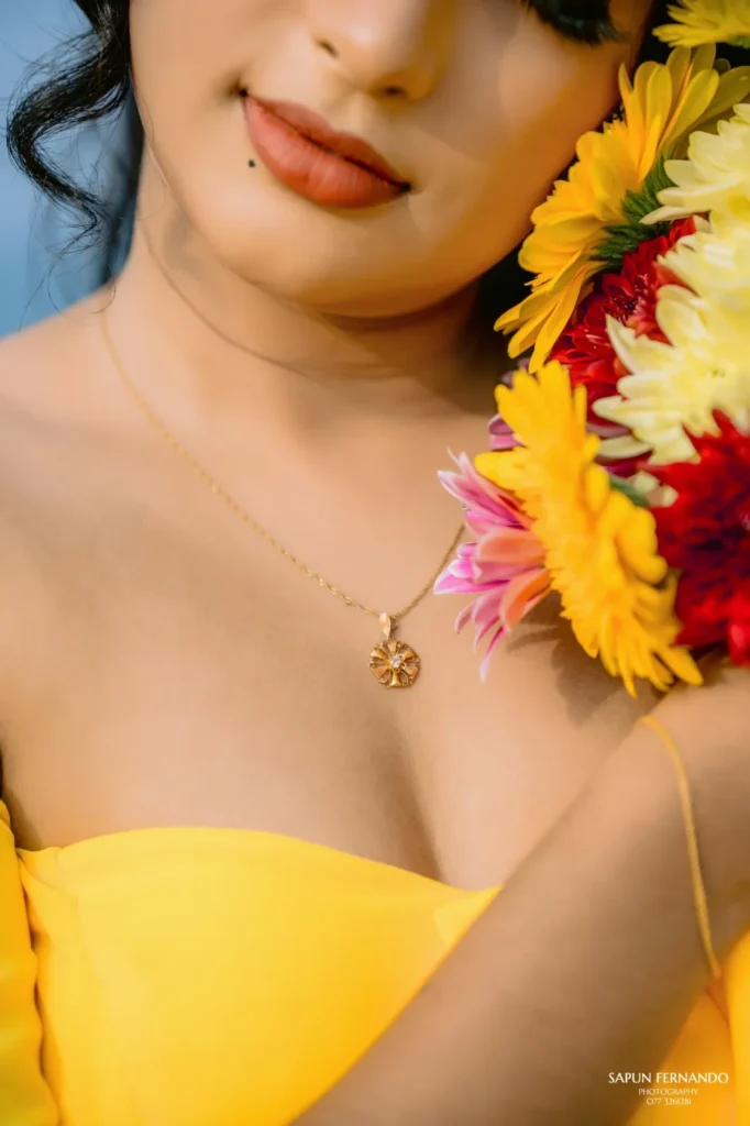 A beautiful young woman in a yellow dress holds a colourful bouquet of flowers, showcasing her beauty.