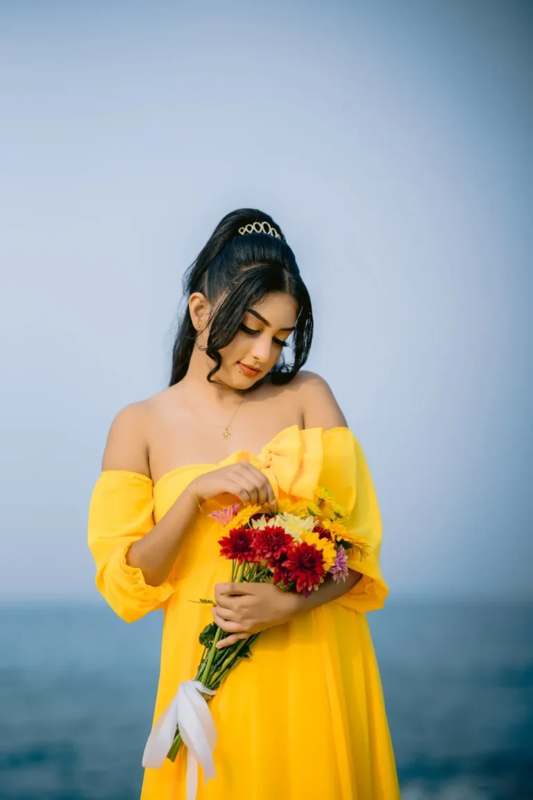 A beautiful young woman in a yellow dress holds a colourful bouquet of flowers, showcasing her beauty.