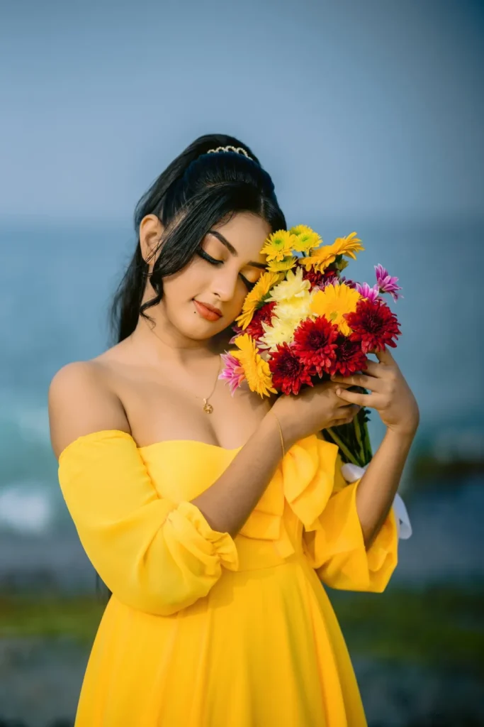 A beautiful young woman in a yellow dress holds a colourful bouquet of flowers, showcasing her beauty.