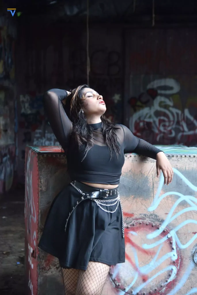 Confident woman posing with fishnet tights and bold expression in urban backdrop.
