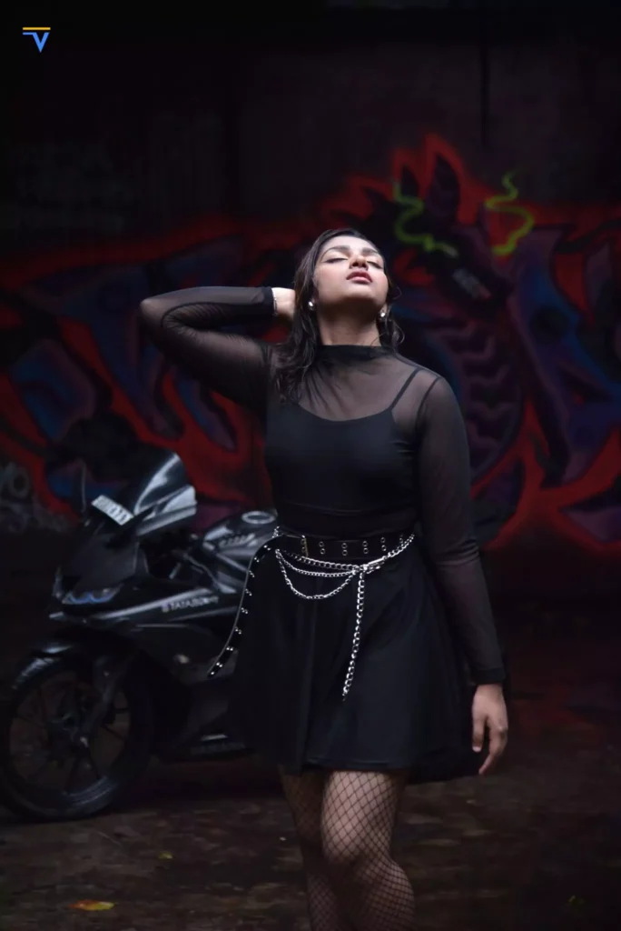 Female model posing under dramatic lighting in front of colourful graffiti.