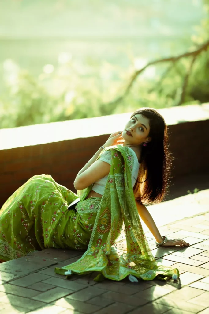 Woman sitting on the pavement in green saree.