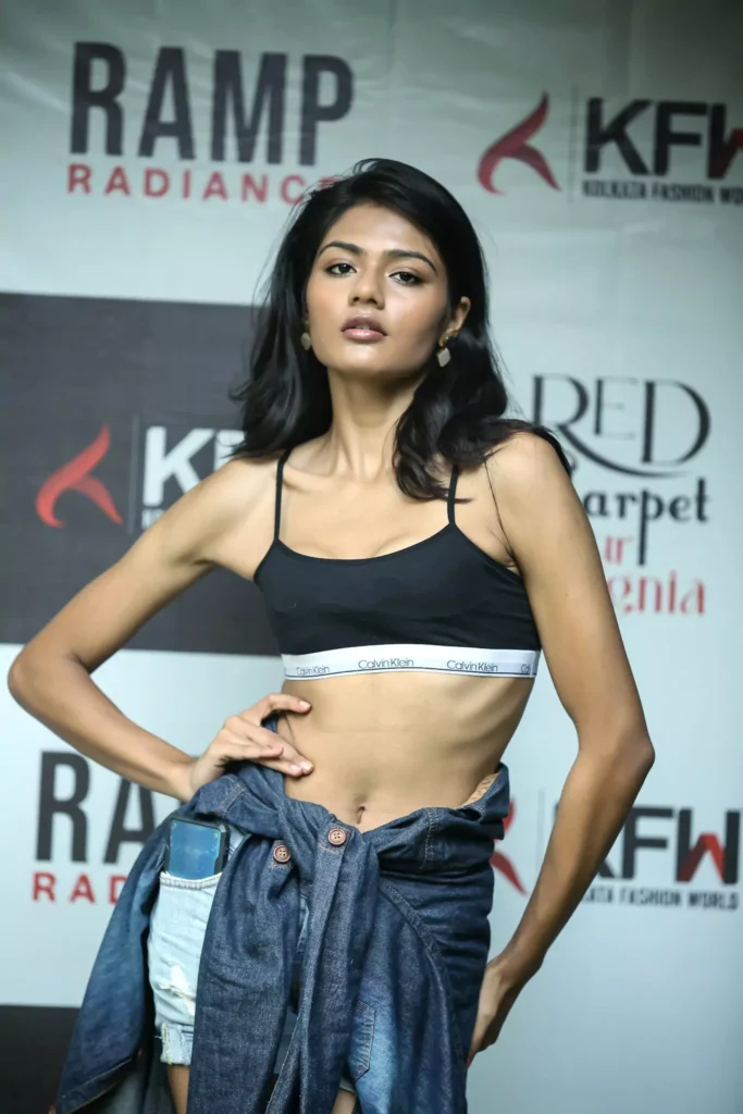 Stylish ramp walk pose in black top and blue denim jacket.