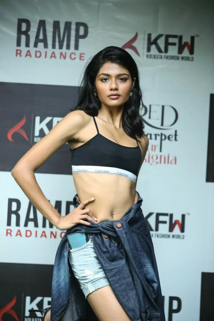 High-fashion ramp pose in a black bralette and denim wrap.