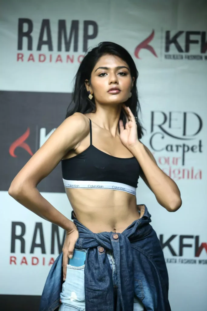 Close-up of model with hand-on-hip pose at a fashion show.